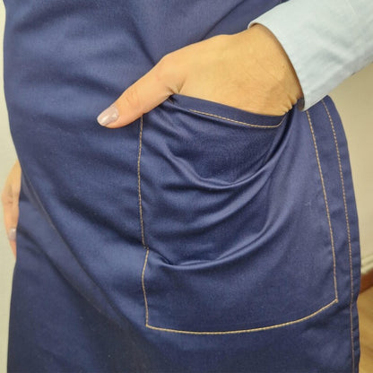 Blue apron with pocket with closure and camel-colored stitching